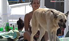 Amatørjente med små pupper leker med en hund på stranden